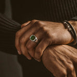 Un homme portant une bague Zaid - Sterling Silver Malachite Signet Ring 13mm avec une pierre émeraude.