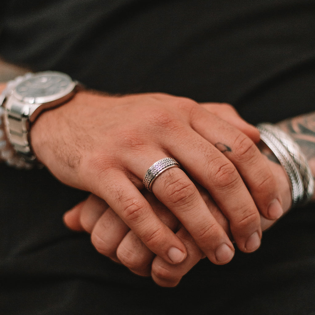 Een man draagt de Hani - Sterling Zilveren Spinner Ring 8mm met een tatoeage op zijn hand.