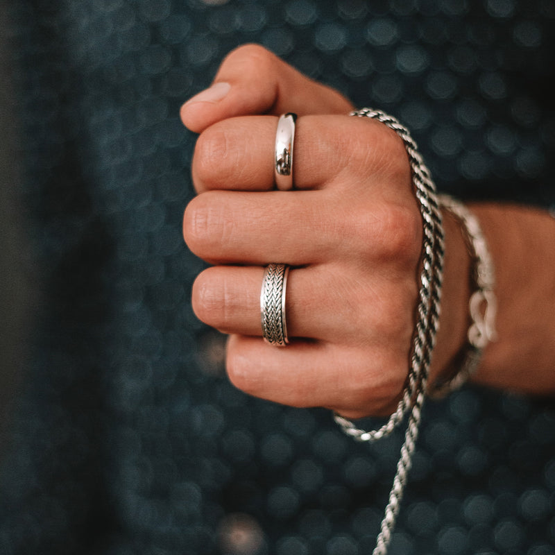 Man wearing the Ninetwofive Hani mens spinner ring while holding the matching sterling silver braided chain.