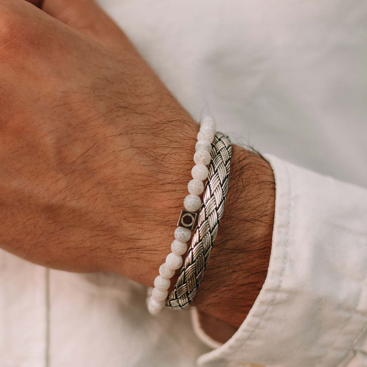 Un homme portant le bracelet Idris - Braided Silver Jonc 8mm avec une pierre blanche.