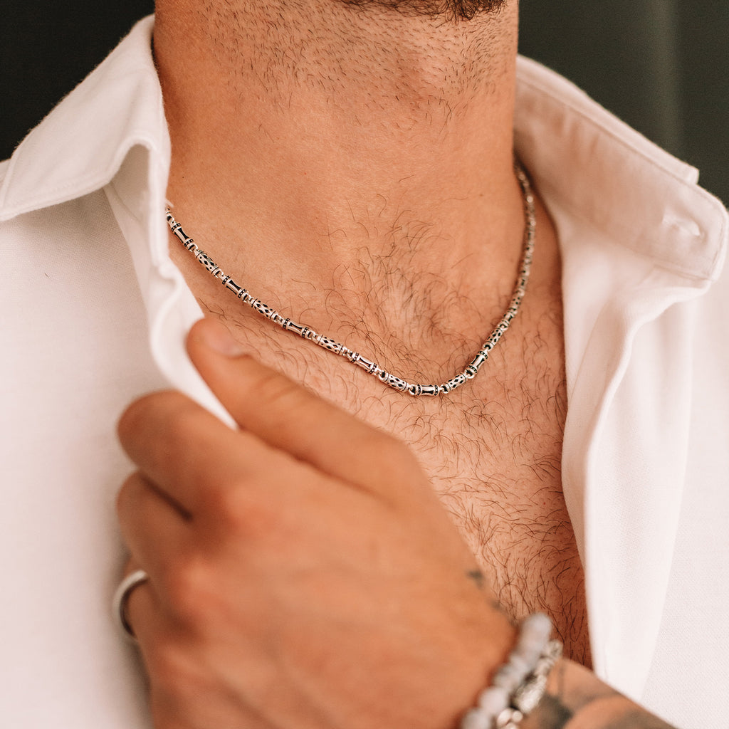 A man wearing a Kadeem - Sterling Silver Ornaments Chain Necklace 3.5mm necklace.