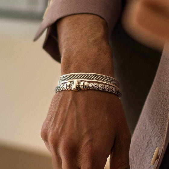 A man in a suit is wearing a NineTwoFive's Mirza sterling silver mens bracelet and a cuff bangle.