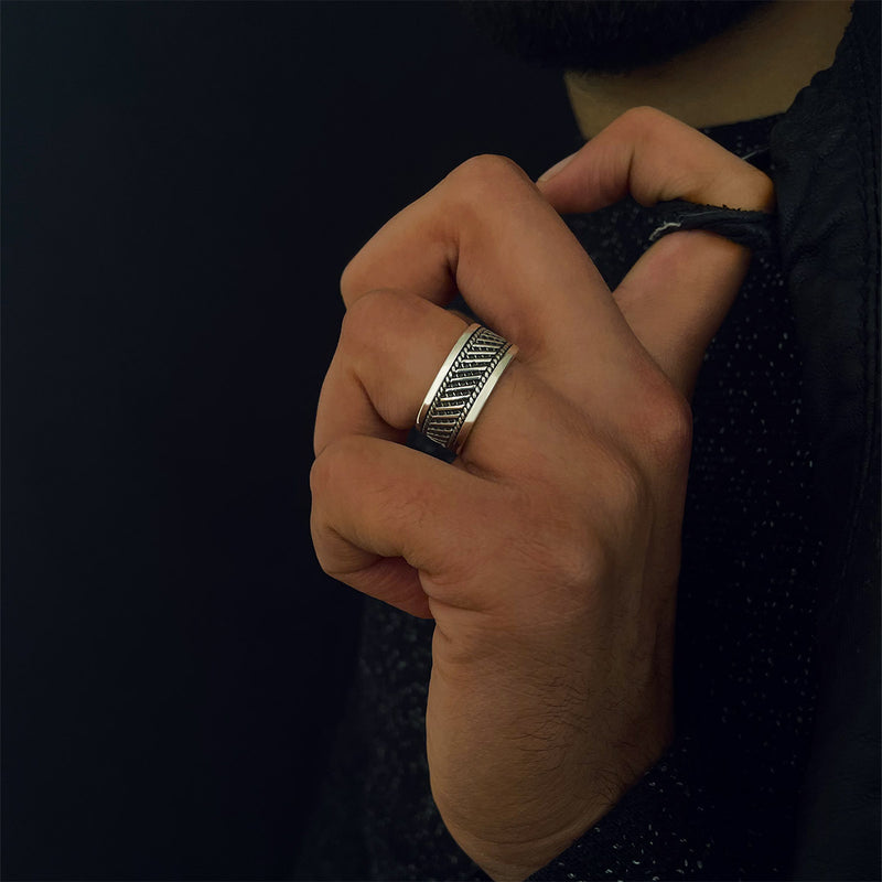 A man wears the Ninetwofive's Kaliq oxidized sterling silver mens ring on his ring finger. 