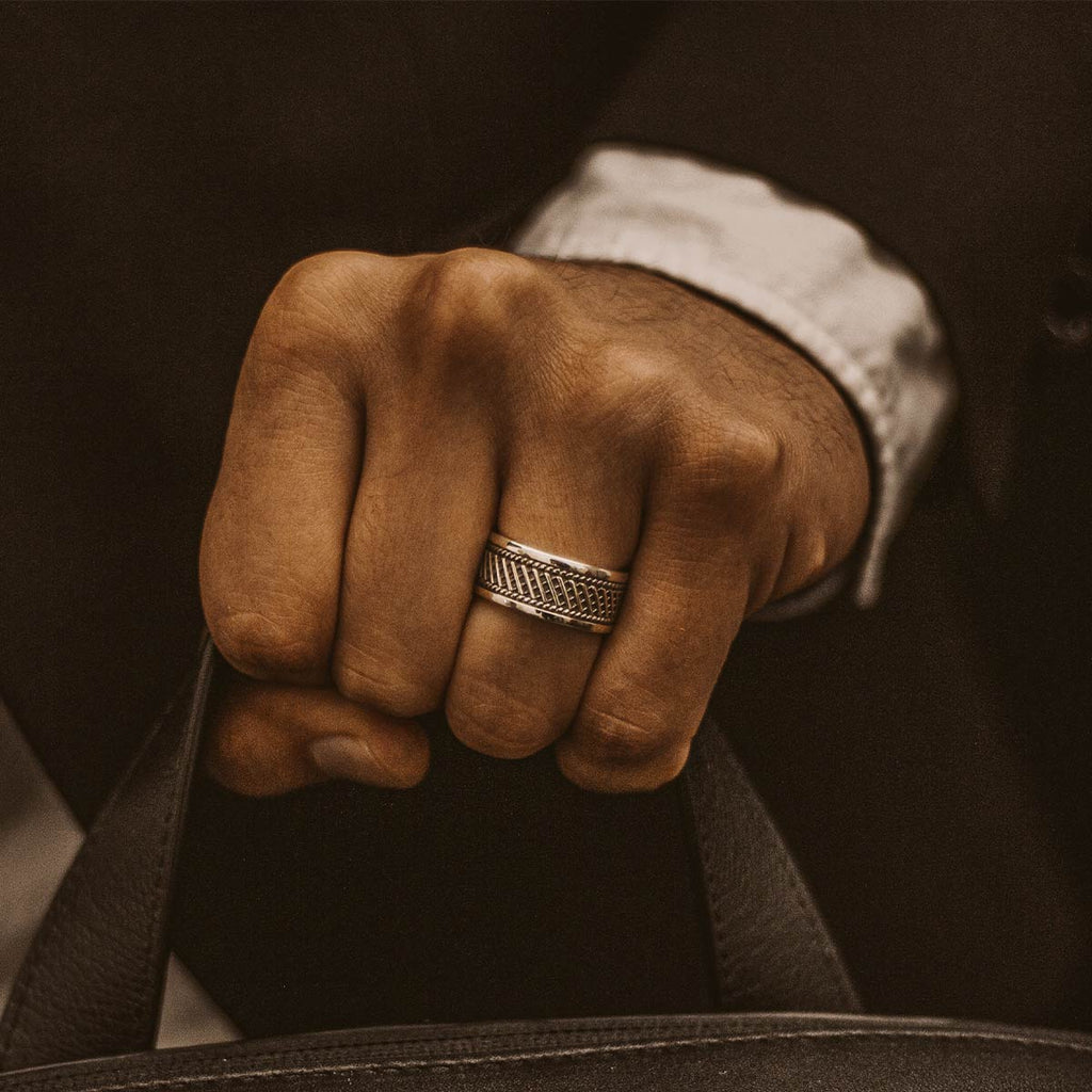 Ein Mann trägt einen Kaliq - Oxidierter Sterling Silber Ring 10mm und hält eine Aktentasche.