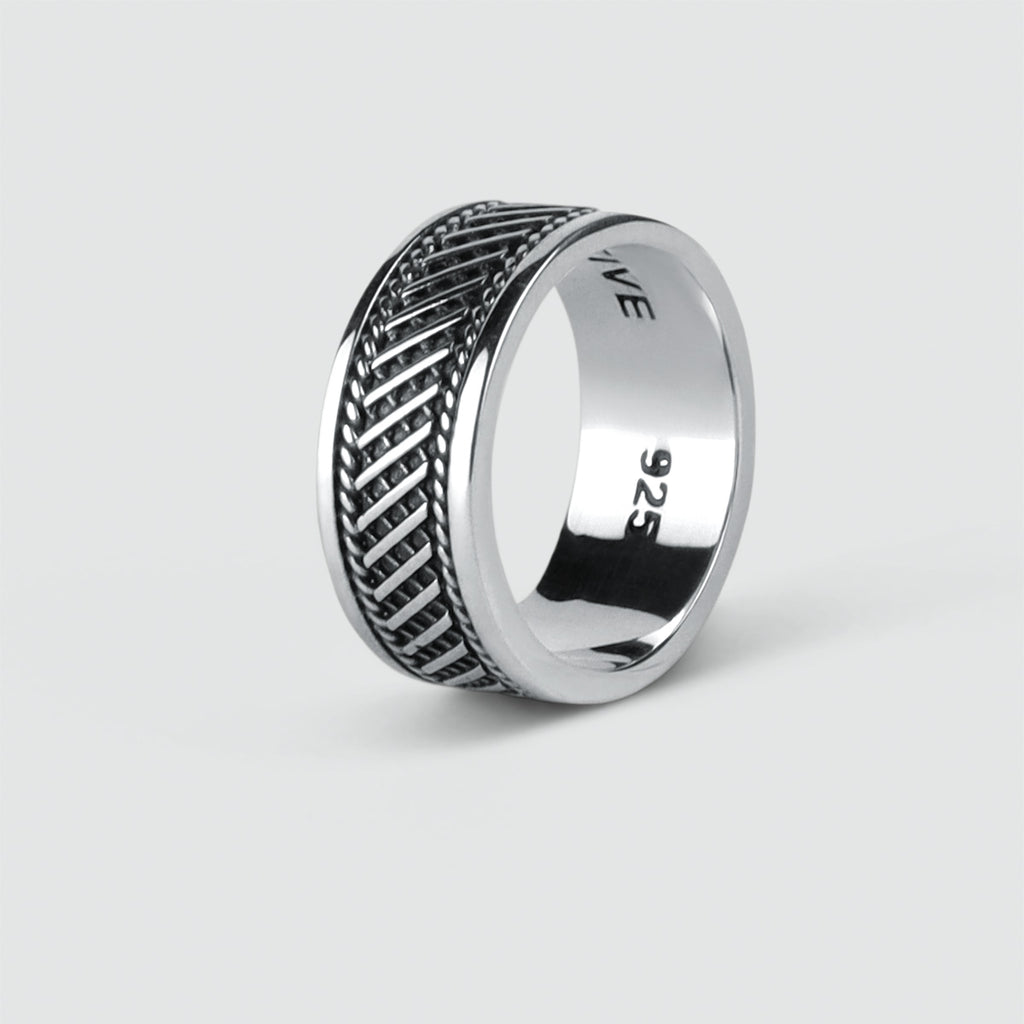 A mens Kaliq - Oxidized Sterling Silver Ring 10mm with an engraved herringbone pattern.