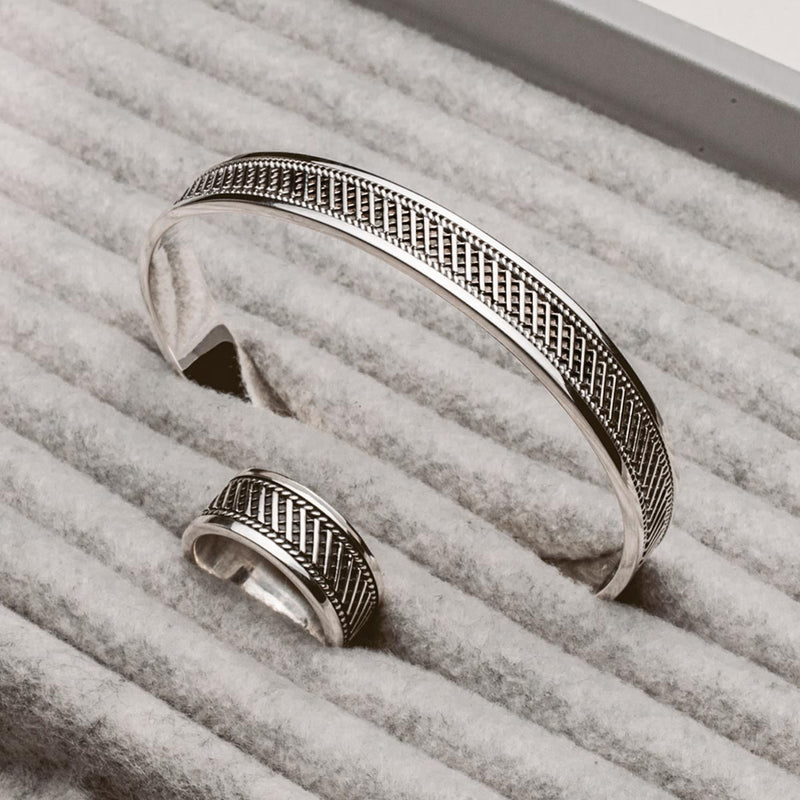 A silver cuff bracelet and ring sitting on top of a box, showcasing the Kaliq oxidized sterling silver mens ring by Ninetwofive.