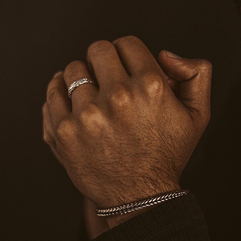 De hand van een man met de Latif - Dunne Sterling Zilveren Gevlochten Ring 5 mm voor hem.