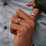 Un homme tient dans sa main une bague Latif - Thin Sterling Silver Braided Ring 5mm.