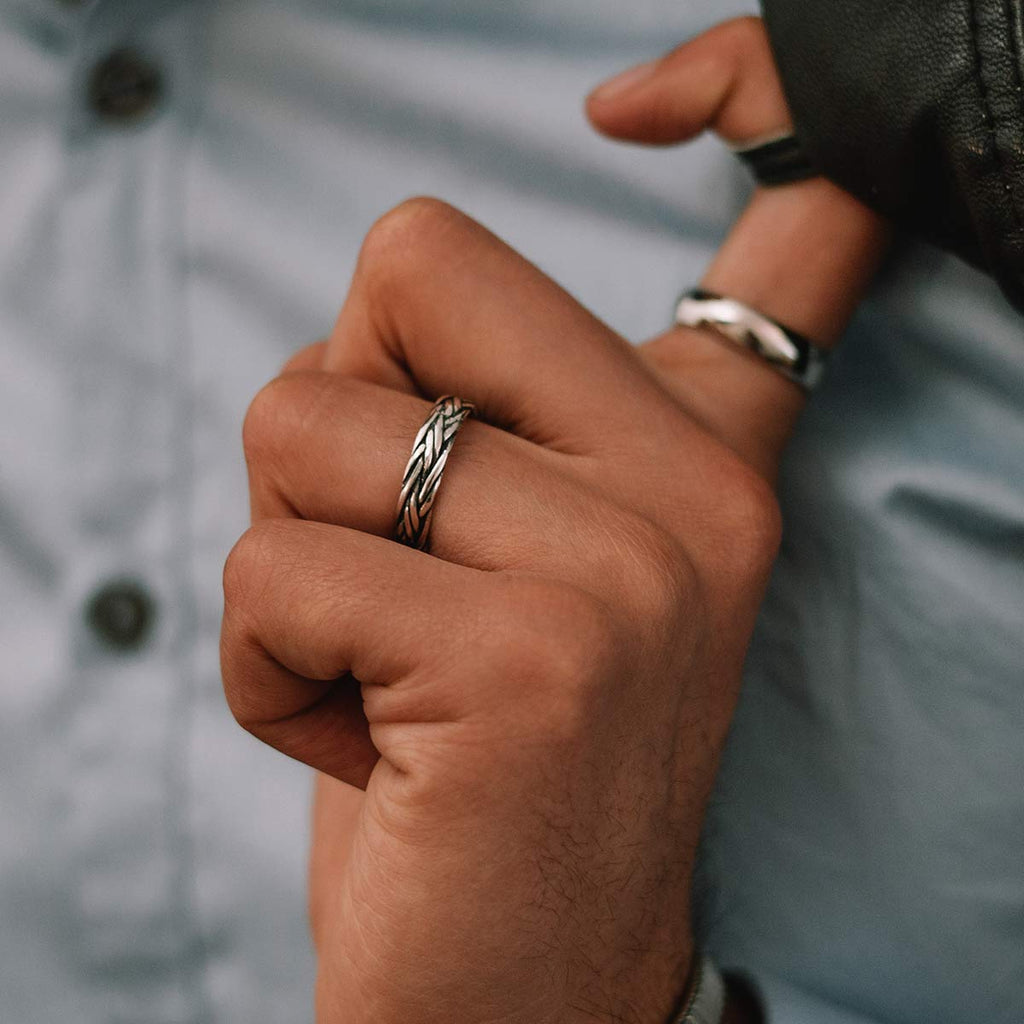 A man is holding a Latif - Thin Sterling Silver Braided Ring 5mm in his hand.