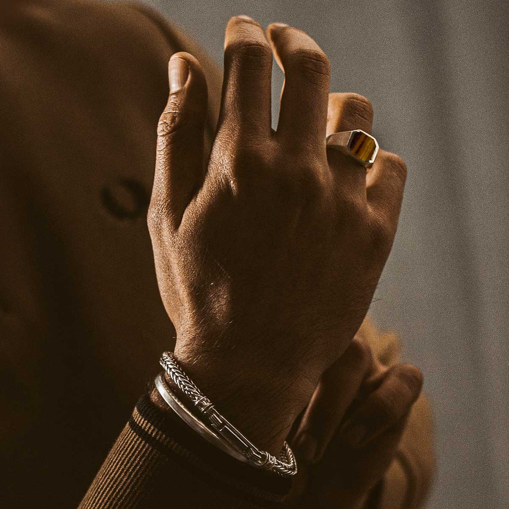 De hand van een man draagt de Alem - Tijgeroogsteen Zegel Ring 13mm.