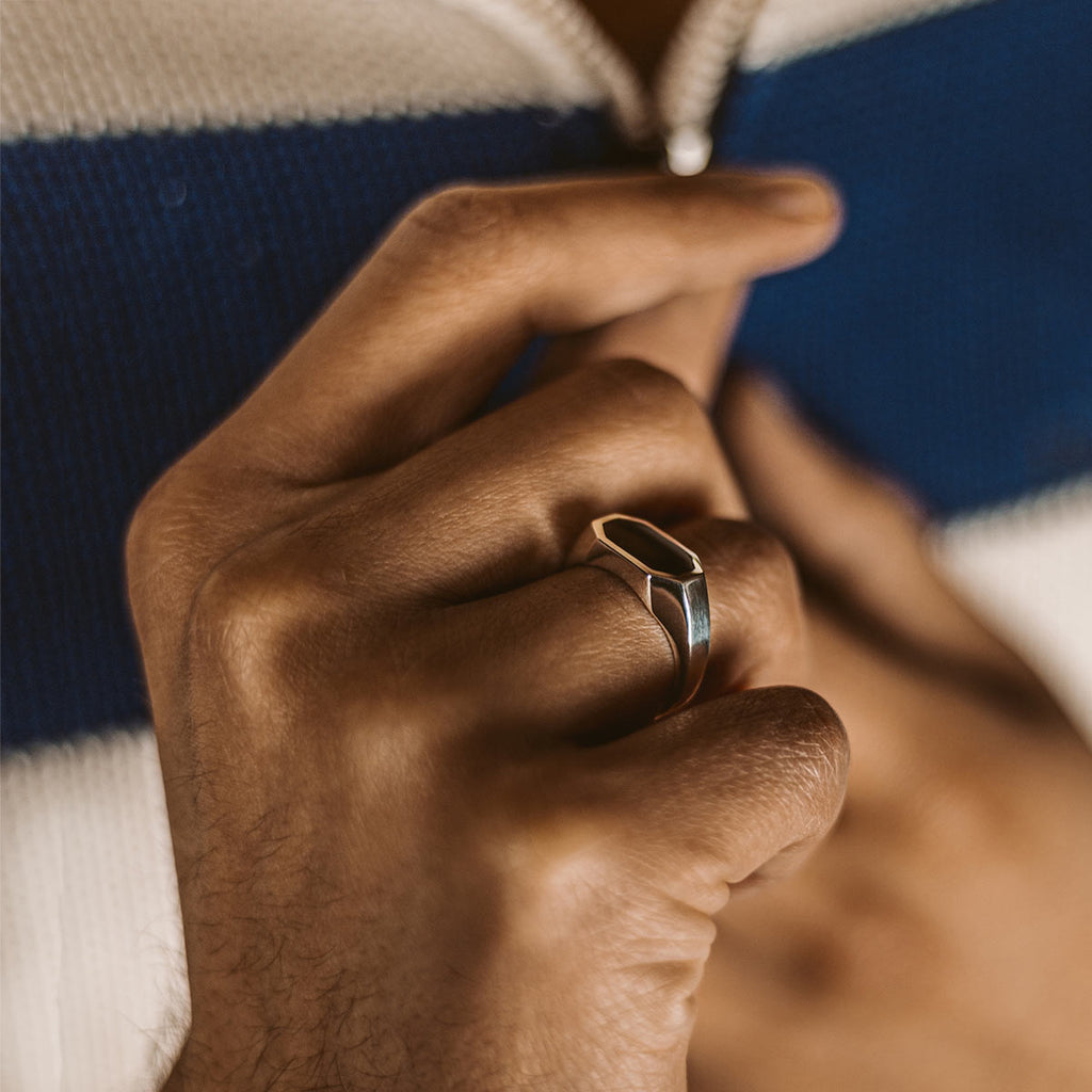 De hand van een man toont trots de Aniq - Elegant Black Onyx Zegel Ring 7mm.