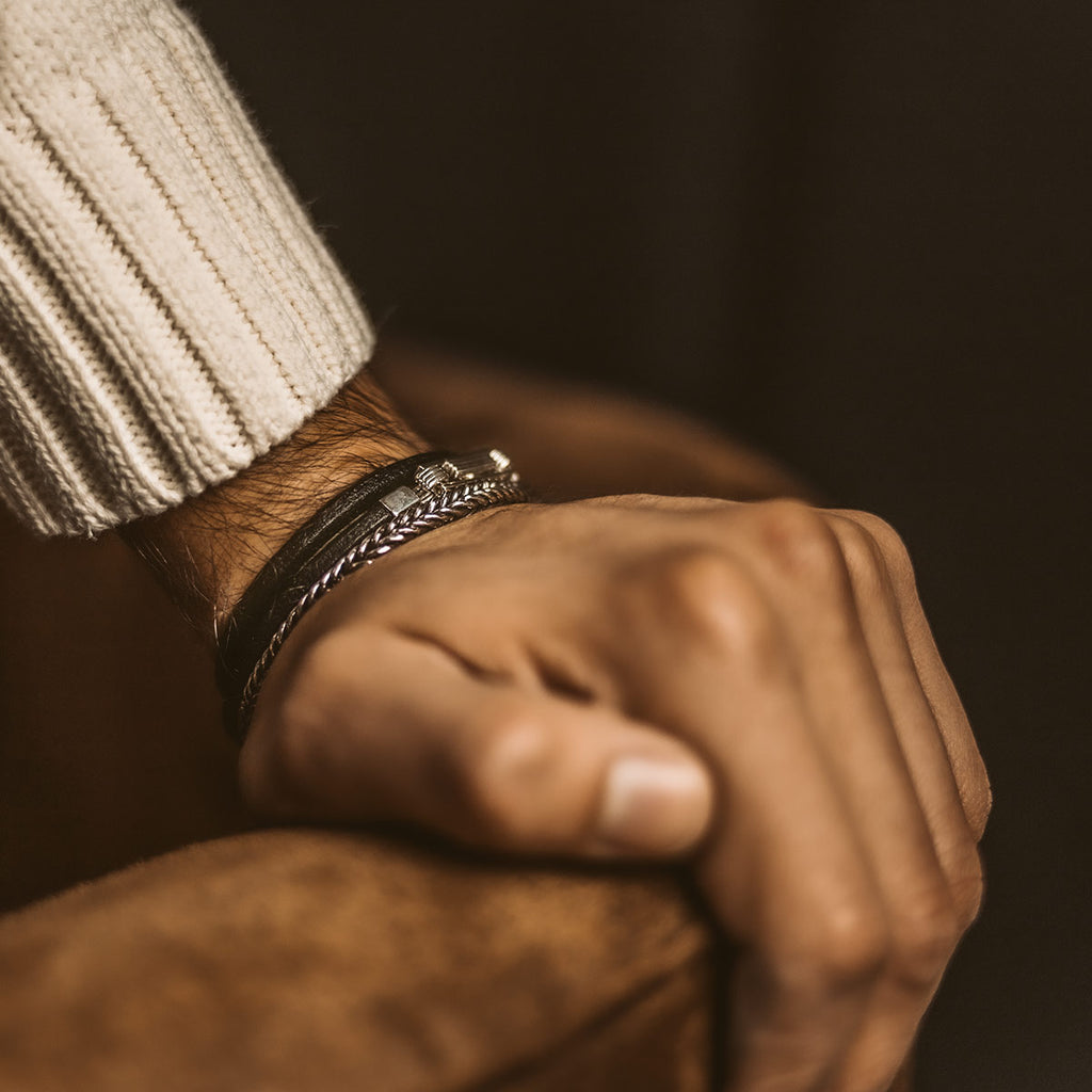 A man wearing a sweater and the Rami - Genuine Black Leather Bracelet 5mm.