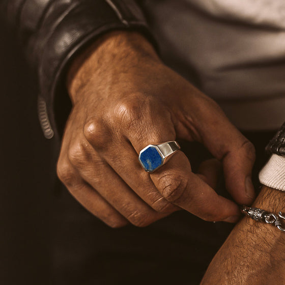 A man in a jacket showing Ninetwofive's Kadar blue lapis lazuli stone signet ring for men and silver bracelet.
