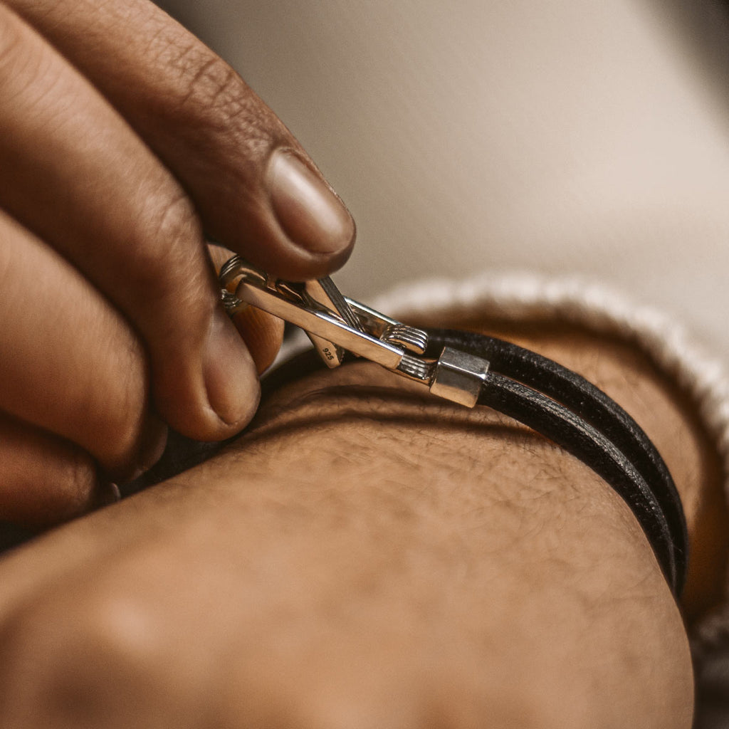 La main d'une personne tient un bracelet Rami en cuir noir véritable de 5 mm.