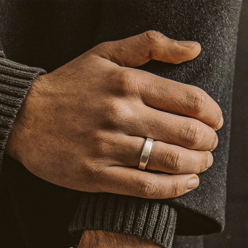 A man's hand with a Tamir - Matt Silver Ring 6mm on it, showcasing an engraved mens silver ring.