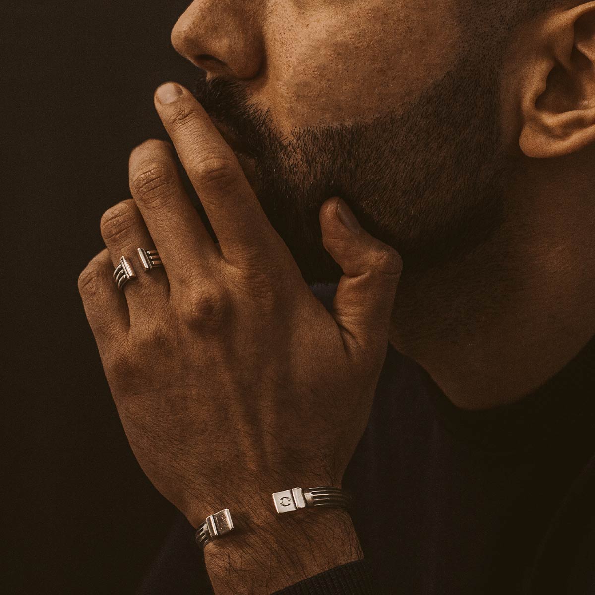 Een man met een baard draagt armbanden en showt zijn stijlvolle Mateen - Geoxideerd Sterling Zilver Bangle Ring 10mm.