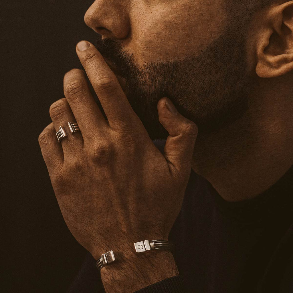 A man with a beard wearing bracelets, showcasing his stylish Mateen - Oxidized Sterling Silver Bangle Ring 10mm.