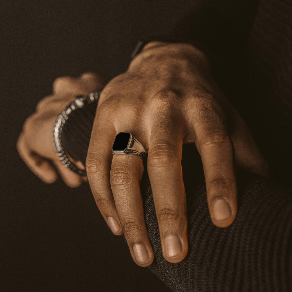 Een man draagt een NineTwoFive Baki - Zwarte Onyx Zegel Ring 17mm.