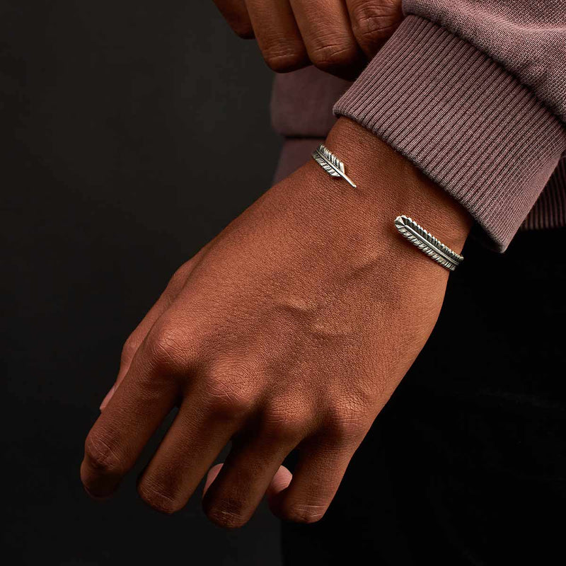 Un homme portant un pull sur lequel figure Zahir, un bracelet pour homme fin en argent massif de la marque Ninetwofive.
