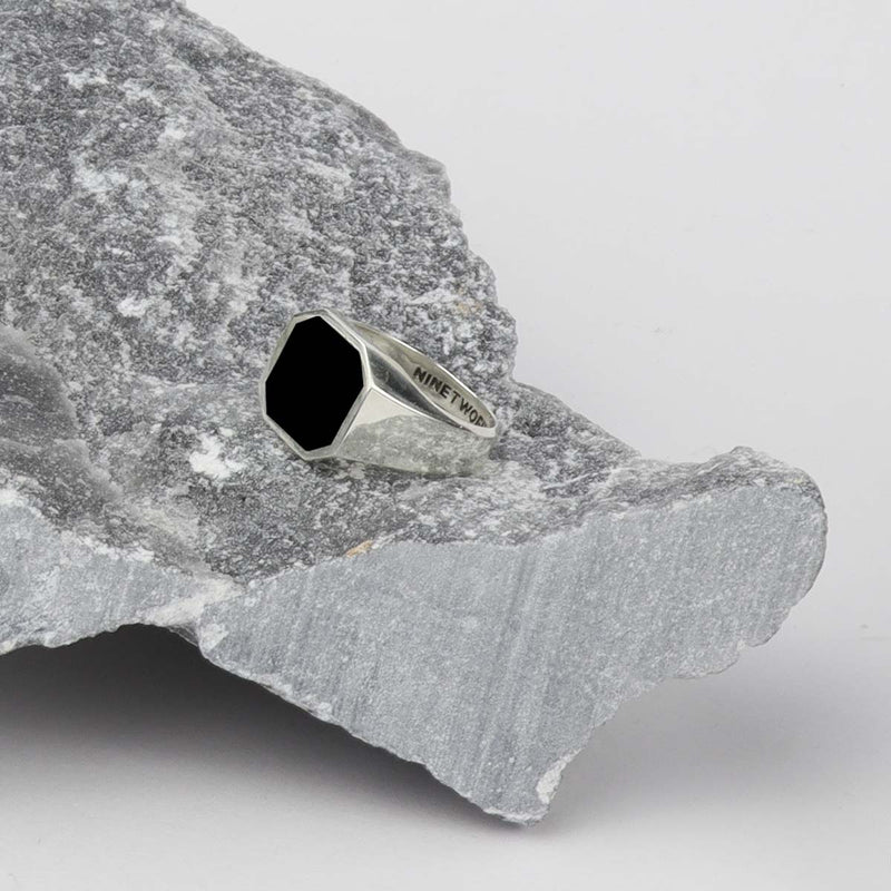 A Naim black onyx sterling silver mens signet ring sitting on top of a rock, Ninetwofive.