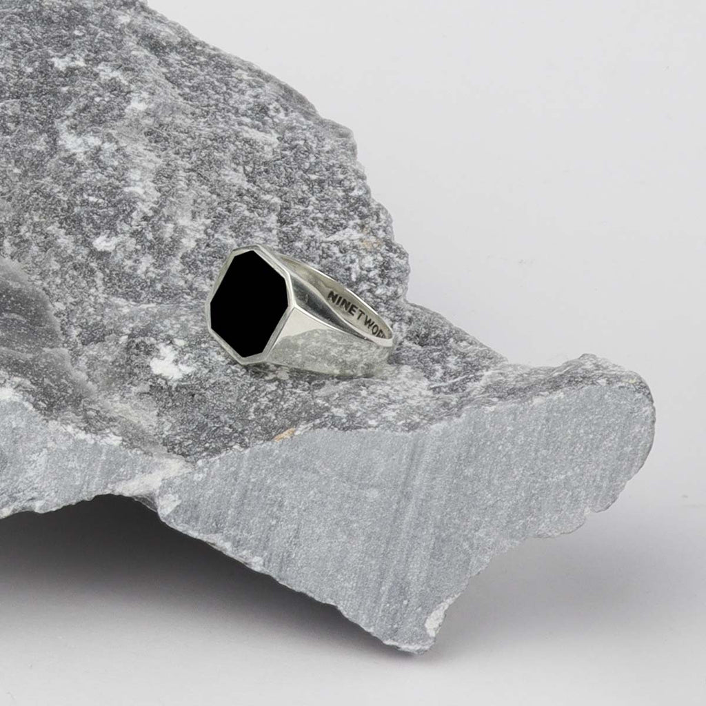 Een Naim - Zwarte Onyx Zegel Ring 13mm bovenop een rots.