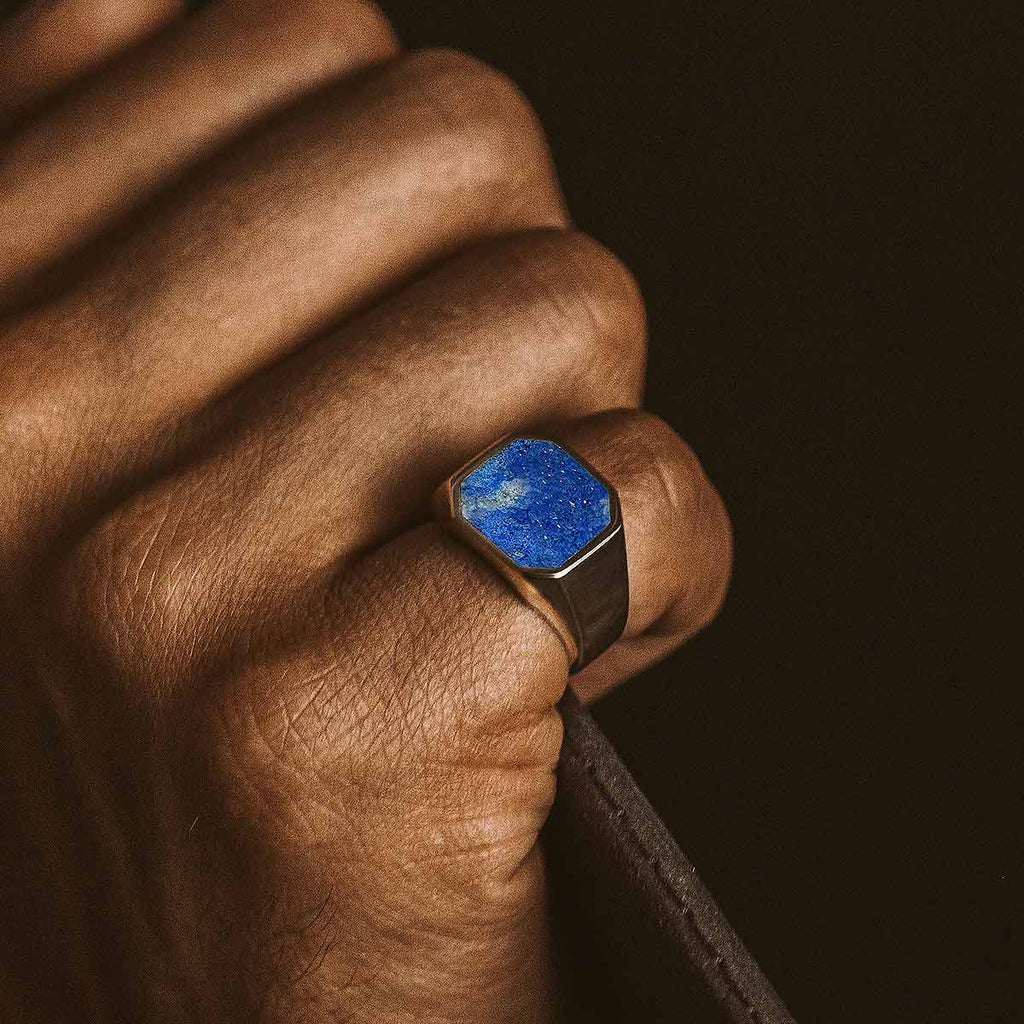 A man wearing a Kadar - Blue Lapis Lazuli Stone Signet Ring 13mm engraved.