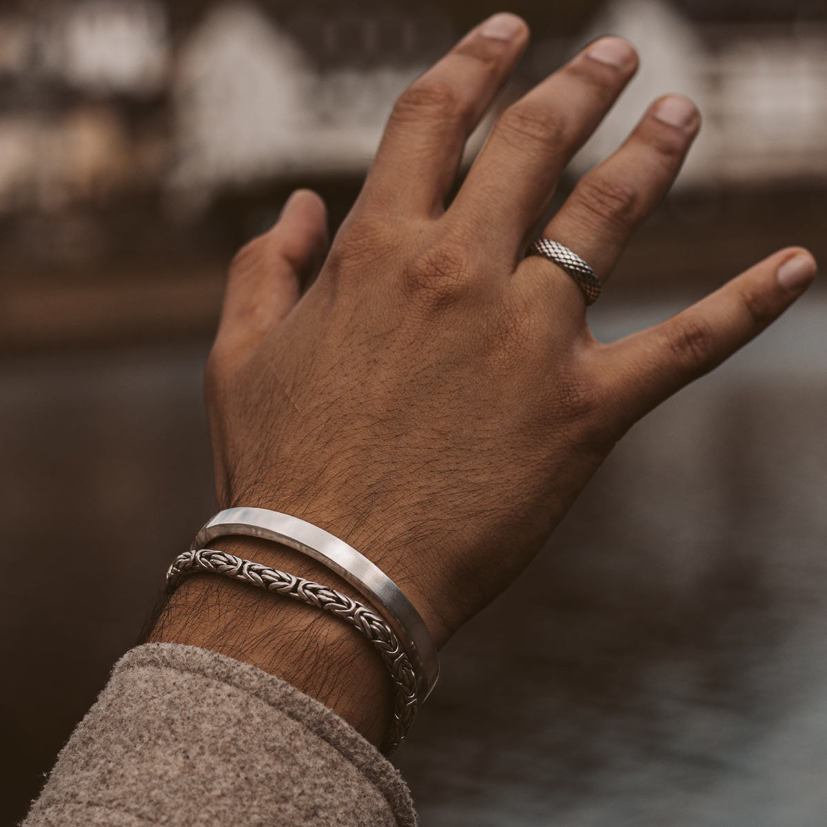 Die Hand eines Mannes mit einer eleganten Boulos - Plain Sterling Silver Armreif 8mm, die sein Handgelenk schmückt.