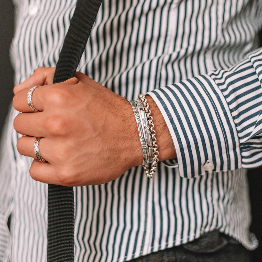 A man wearing a striped shirt and suspenders accessorized with an Ishak - Sterling Silver Chain Link Bracelet 6mm.