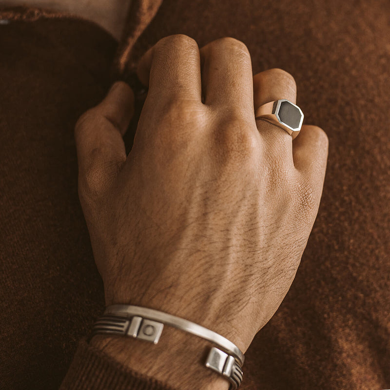 A man wearing a Naim black onyx mens signet ring and silver cuff bracelet by Ninetwofive.