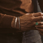 Un homme portant un bracelet Boulos - Plain Sterling Silver Jonc 8mm avec une pierre émeraude.