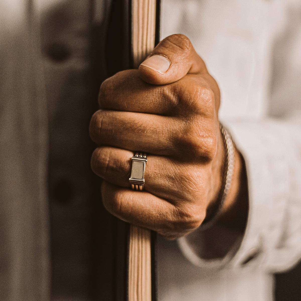 A man's hand confidently displaying a book embellished with the Imad - Sterling Silver Pillar Signet Ring 8mm.