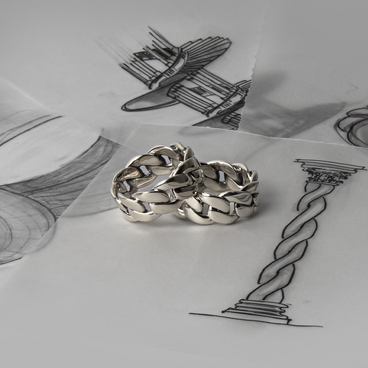 Ein Paar Rayen - Silber Cuban Link Ring 9mm auf der Spitze einer Zeichnung.