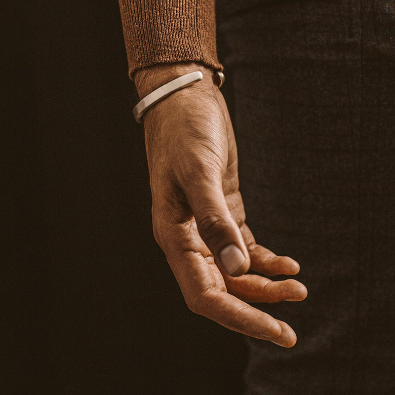 Die Hand eines Mannes trägt den Boulos – schlichten Sterling-Silber-Armreif, 8 mm.
