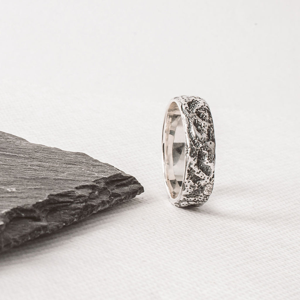 A Tarif - Unique Sterling Silver Ring 7mm engraved for him, placed on a piece of slate.