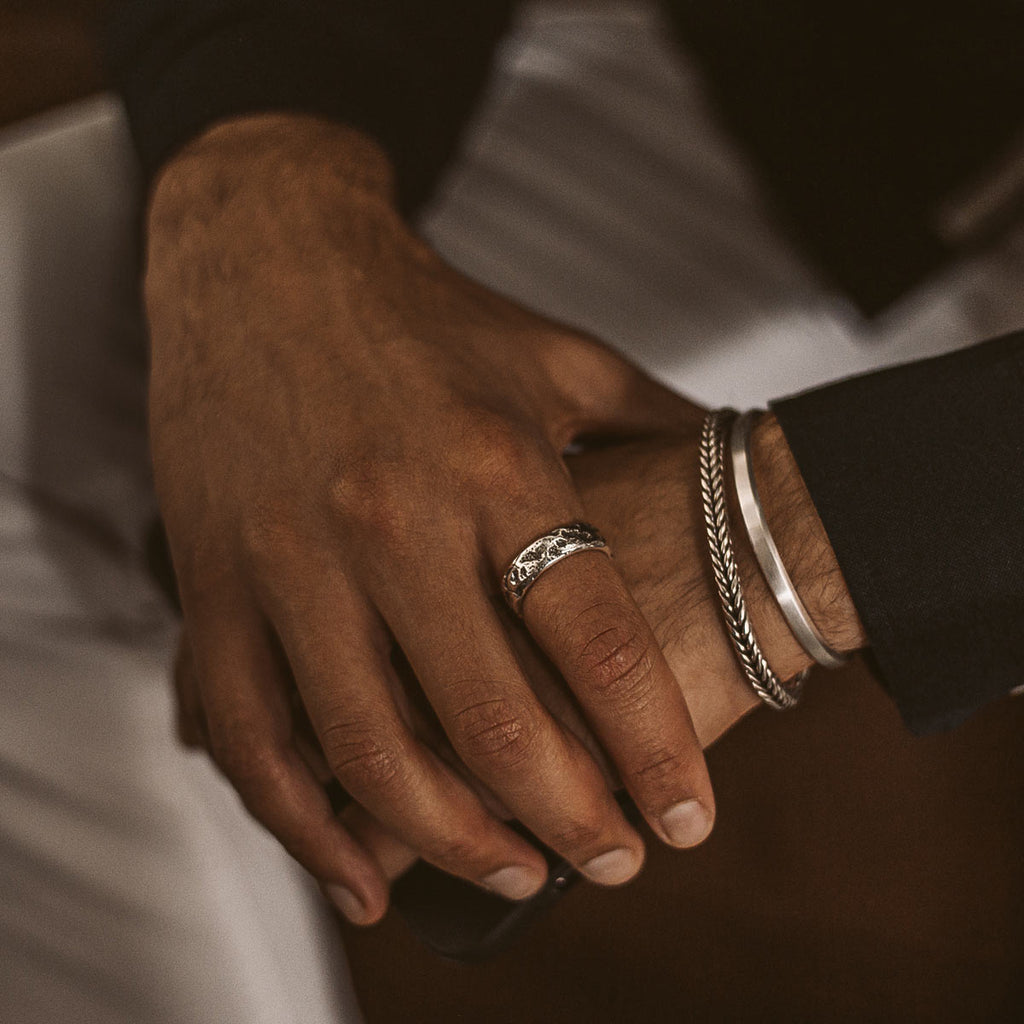 Een man draagt de Tarif - Unieke Sterling Zilveren Ring 7mm op zijn hand.
