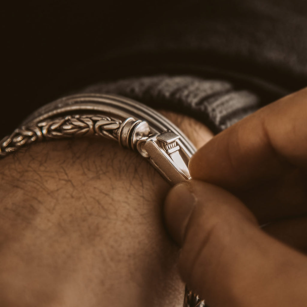 A man is putting on a NineTwoFive - Turath - Sterling Silver Byzantine Kings Bracelet 5mm for men.