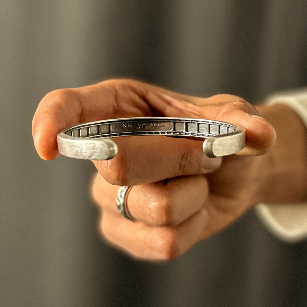 A person showcasing a Fudail - Rough Brushed Sterling Silver Bangle 8mm.