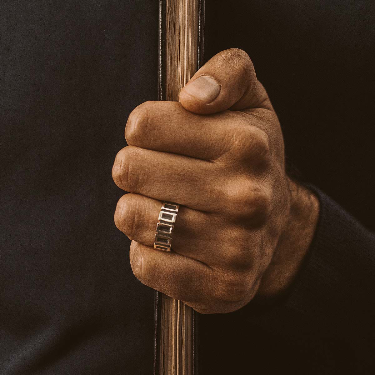 A man wearing a Yardan - Oxidized Sterling Silver Ring 8mm while holding a book.