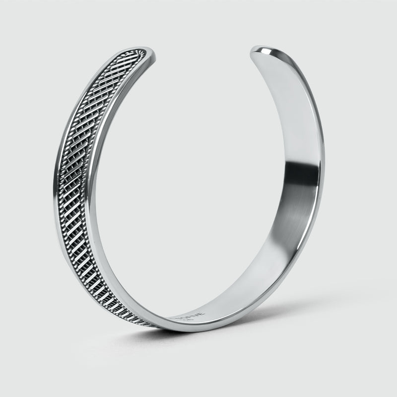 Zijaanzicht van de Kaliq-bangle van geoxideerd sterlingzilver, 10 mm, met een geweven patroon. Ninetwofive.