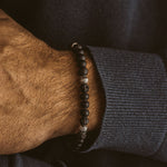 A man wearing a Kaliq - Adjustable Onyx Black Beaded Bracelet in Silver 6mm with lava stone.