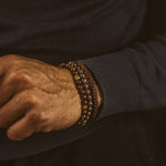 A man wearing the Kaliq - Adjustable Tiger Eye Beaded Bracelet in Gold 6mm.