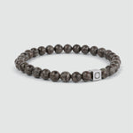 An Albuna - Brown Beaded Bracelet 6mm with a snowflake stone bead and a silver charm.